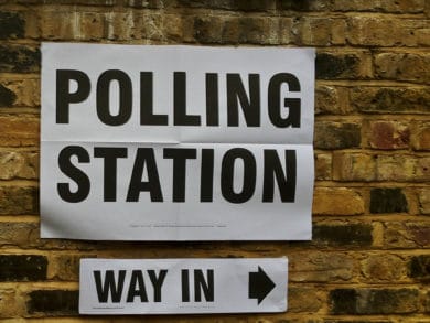 Polling station sign on brick wall