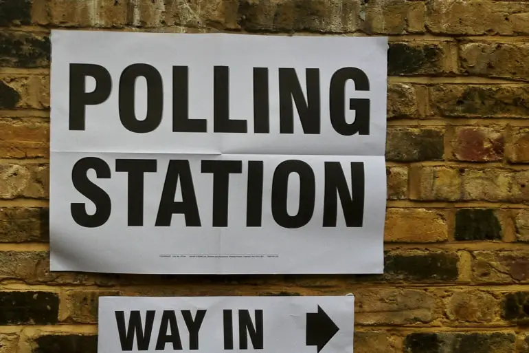 Polling station sign on brick wall