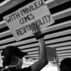 Protst banner reading 'with privilege comes responsibility'