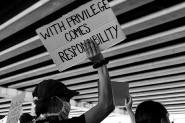 Protst banner reading 'with privilege comes responsibility'
