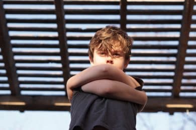 Young boy looking unhappy with arms crossed across body