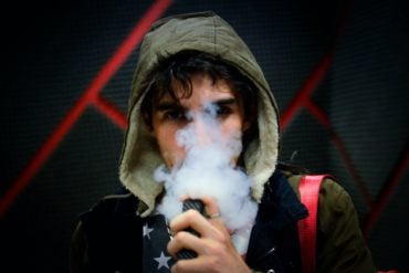 Young person vaping with lots of smoke around their face