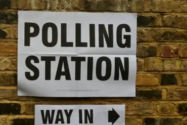 Polling station sign taped to a brick wall