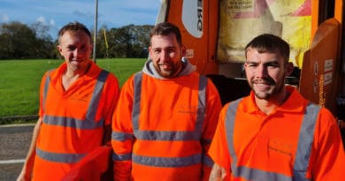 Three bin men at the back of the truck