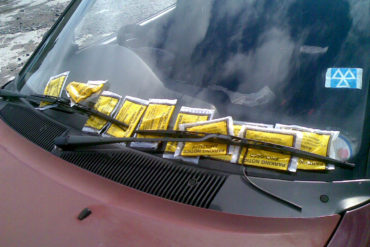 loads of parking tickets on the windscreen of a car