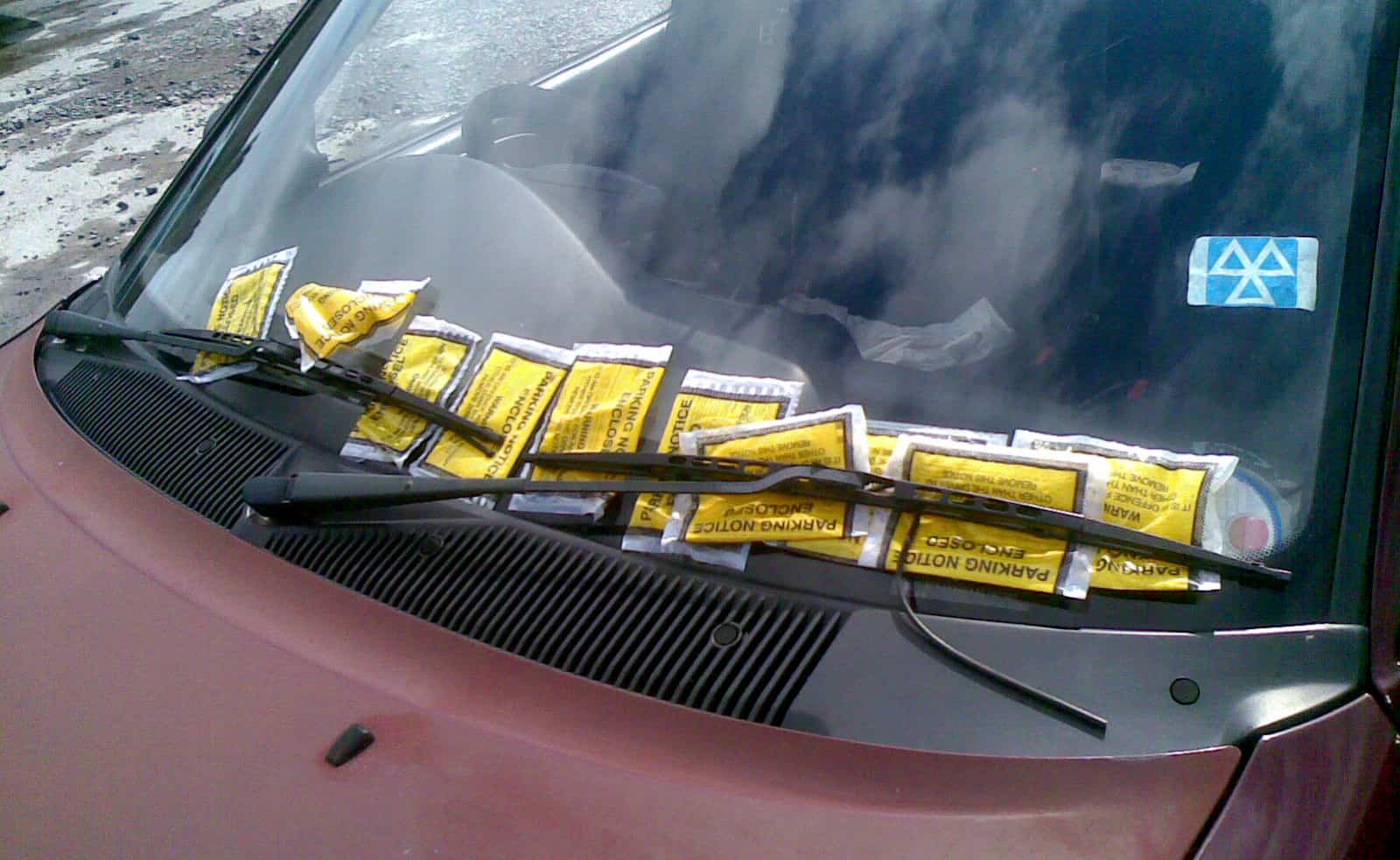 loads of parking tickets on the windscreen of a car