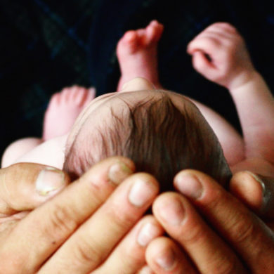 newborn baby cradled in man's hands