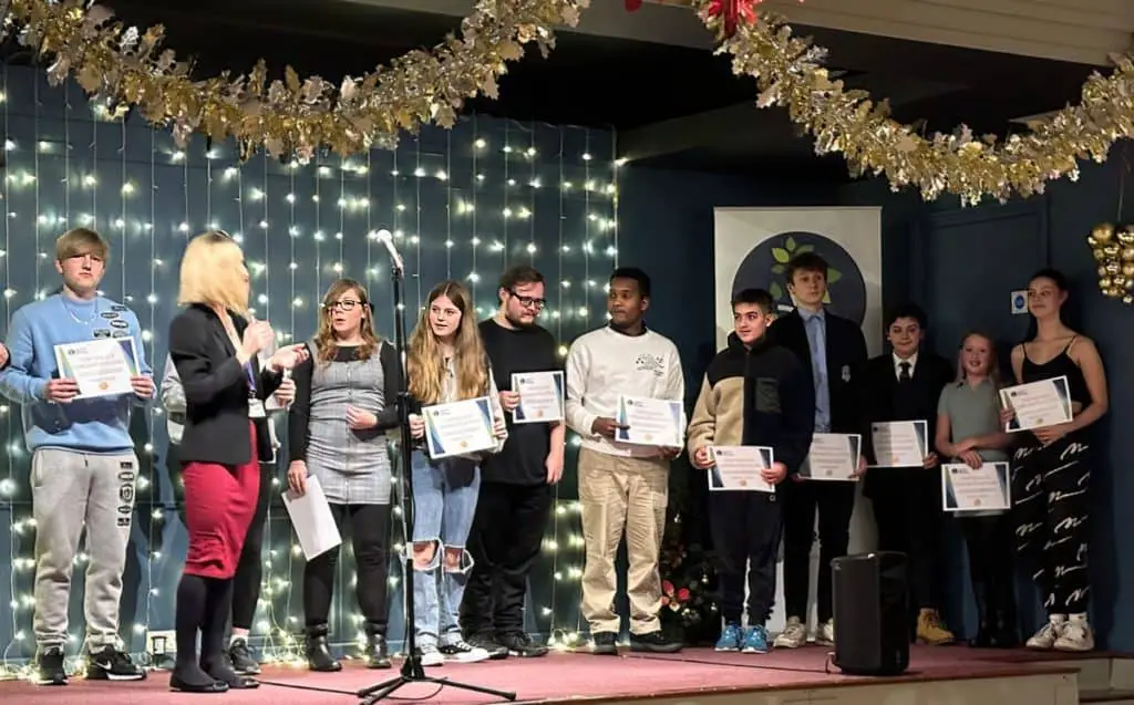 Zoe on stage with young people collecting awards