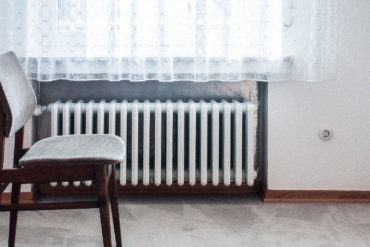 chair in front of window with radiator underneath it by dominik kuhn