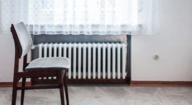 chair in front of window with radiator underneath it by dominik kuhn