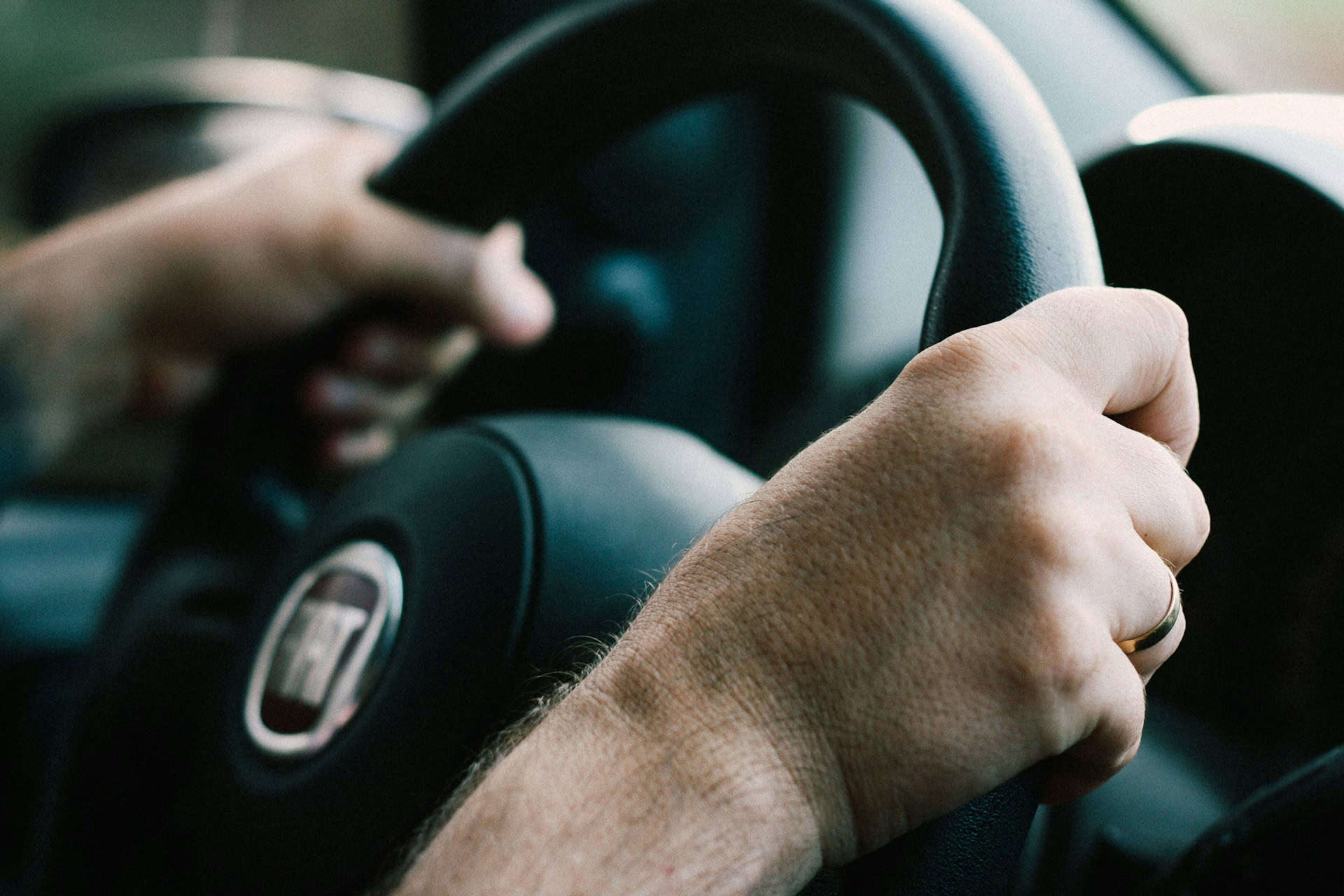 man with hands on car steering wheel