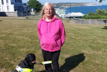 Emily brothers and her guide dog, Truffle, with View of Sandown Bay in the background