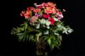 Bouquet of red flowers in vase on table with black background