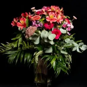 Bouquet of red flowers in vase on table with black background
