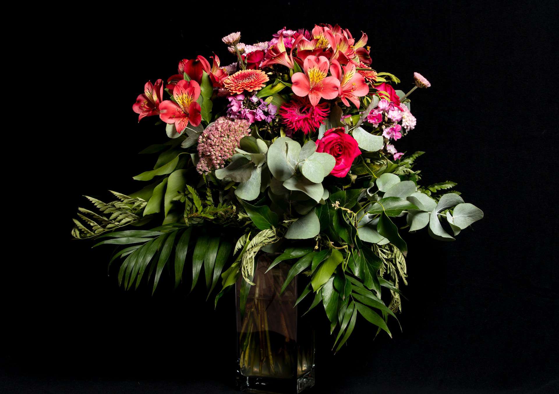 Bouquet of red flowers in vase on table with black background