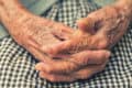 Close up of older woman sat with her hands clasped together