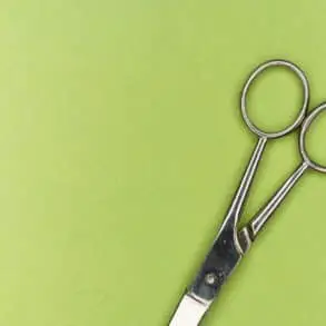 Pair of scissors on green background