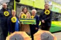 Southern Vectis staff with staff and CEO from Mountbatten Hospice standing by a bus with Sunflower umbrellas