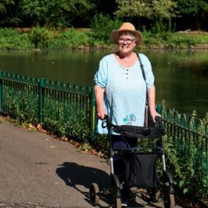 Woman with walking aid in the park by a pond