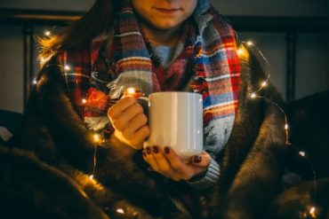 Woman wrapped in blanket and drinking a hot drink