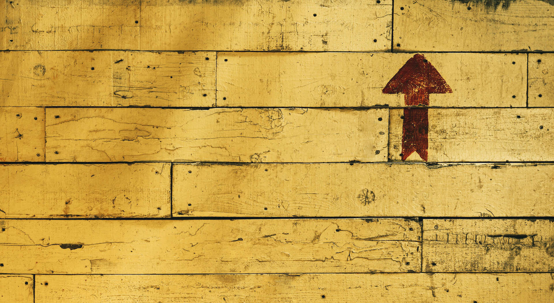 Yellow wooden panelling with brown arrow pointing up