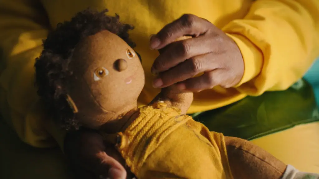 close up of Woman dressed in yellow sitting on bed holding a teddy