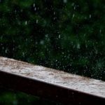 close up of rain hitting a timber railing