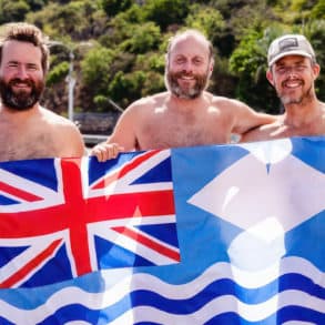 Paul Berry, Xavier Baker and Chris Mannion holding a large British and Isle of Wight flag