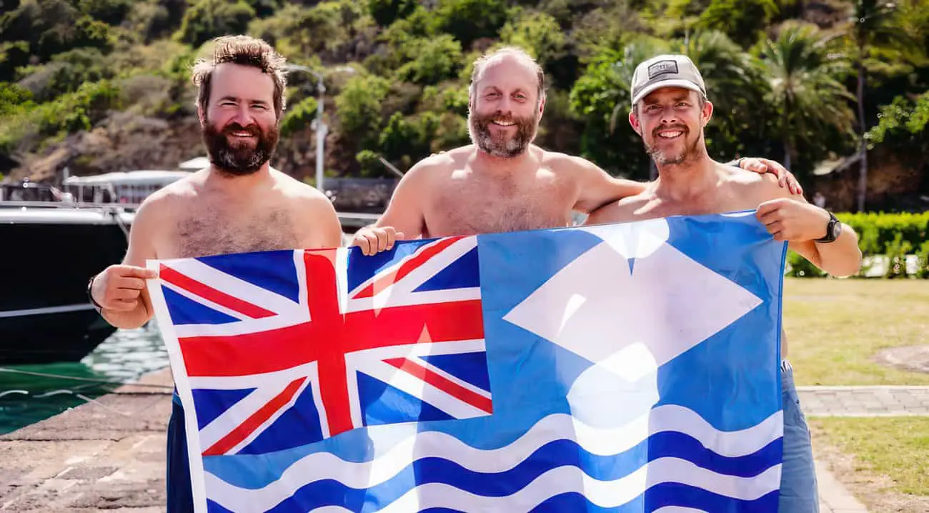 Paul Berry, Xavier Baker and Chris Mannion holding a large British and Isle of Wight flag