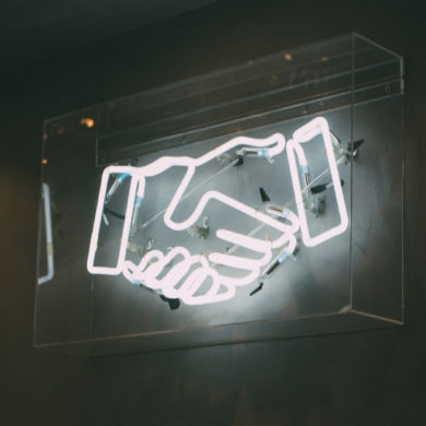 neon sign with handshake on dark background