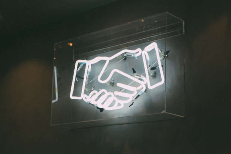 neon sign with handshake on dark background