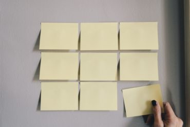 nine yellow post it notes on a board