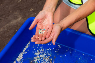 Nurdles being held in the palm of someone's hand on the beach