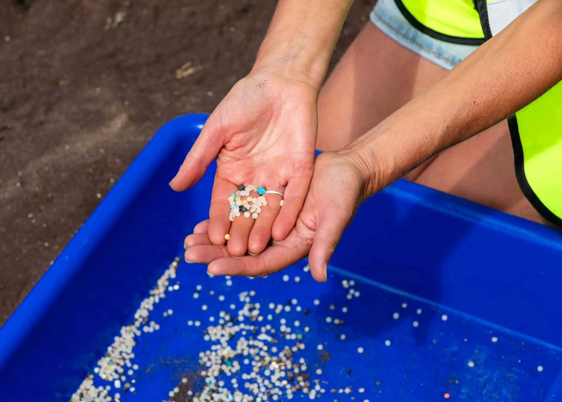 Nurdles being held in the palm of someone's hand on the beach