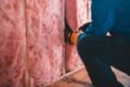 person fitting pink insulation in a home