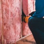 person fitting pink insulation in a home