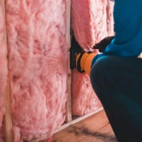 person fitting pink insulation in a home