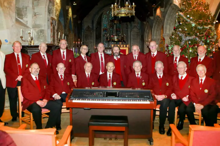 Newchurch Male voice choir standing around an organ