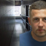 Mugshot of Louis Fletcher with jail corridor in background
