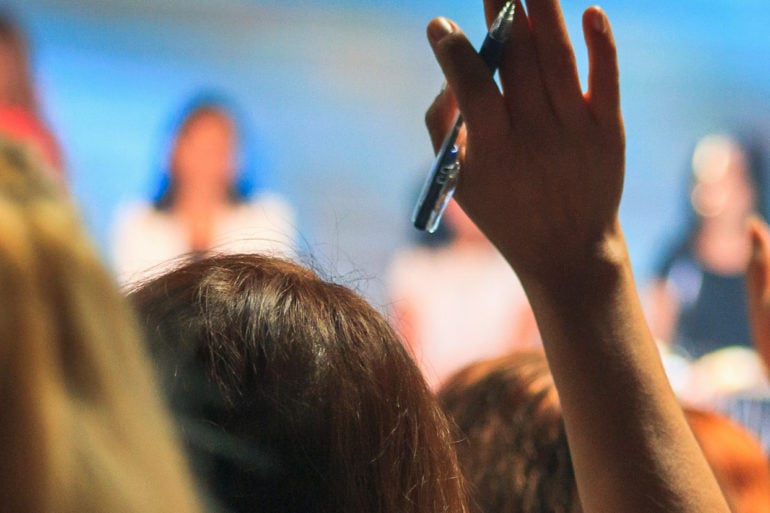 people in an audience putting their hands up