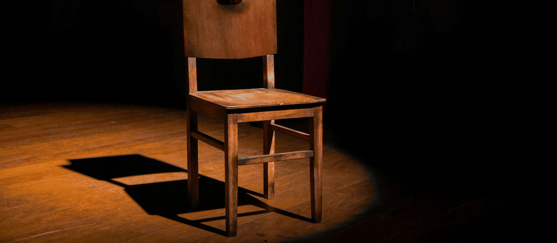 spotlit empty chair on a dark stage