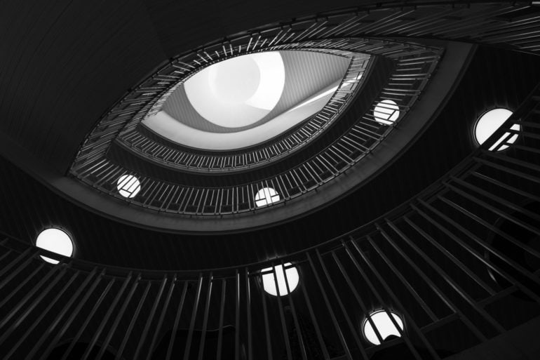 view from bottom of swirling staircase with spotlights on each level