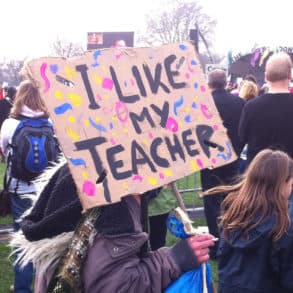 'I like my teacher' banner being held by young person in crowd at rally