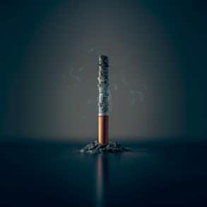 Smoking cigarette balanced on filter with ash around it