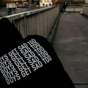 Youth wearing a hoodie with Boys Get Sad Too printed on the back