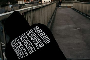 Youth wearing a hoodie with Boys Get Sad Too printed on the back