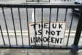 handmade sign attached to railings in London that reads 'the UK is not innocent'