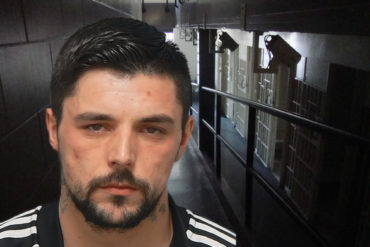 Mugshot of Connor Barnes with jail corridor in background