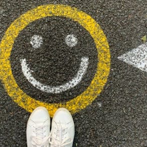 person standing by smiley face painted on tarmac
