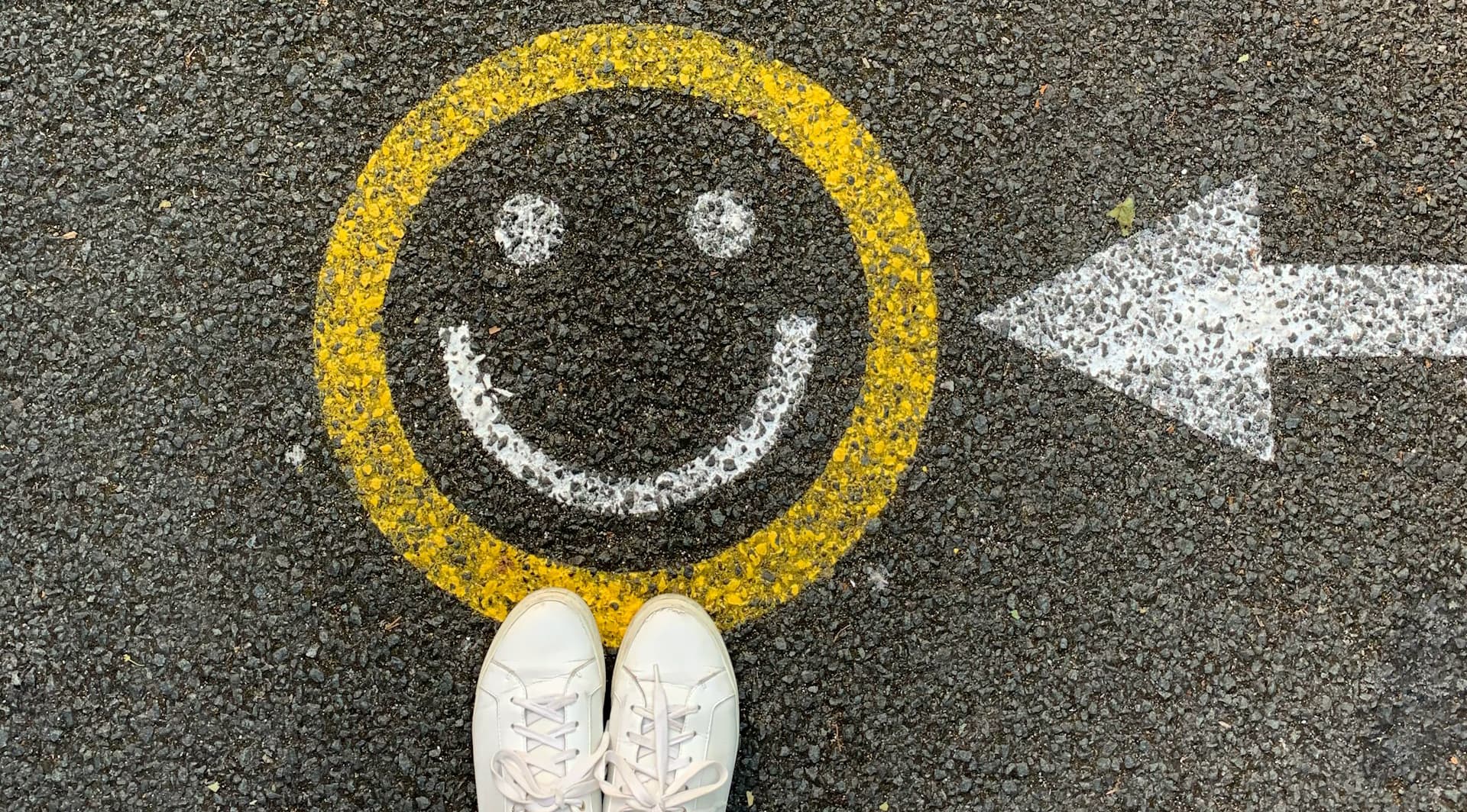 person standing by smiley face painted on tarmac